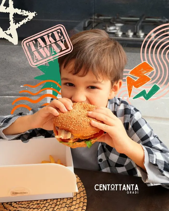 Un bambino mangia un burger take away con patatine